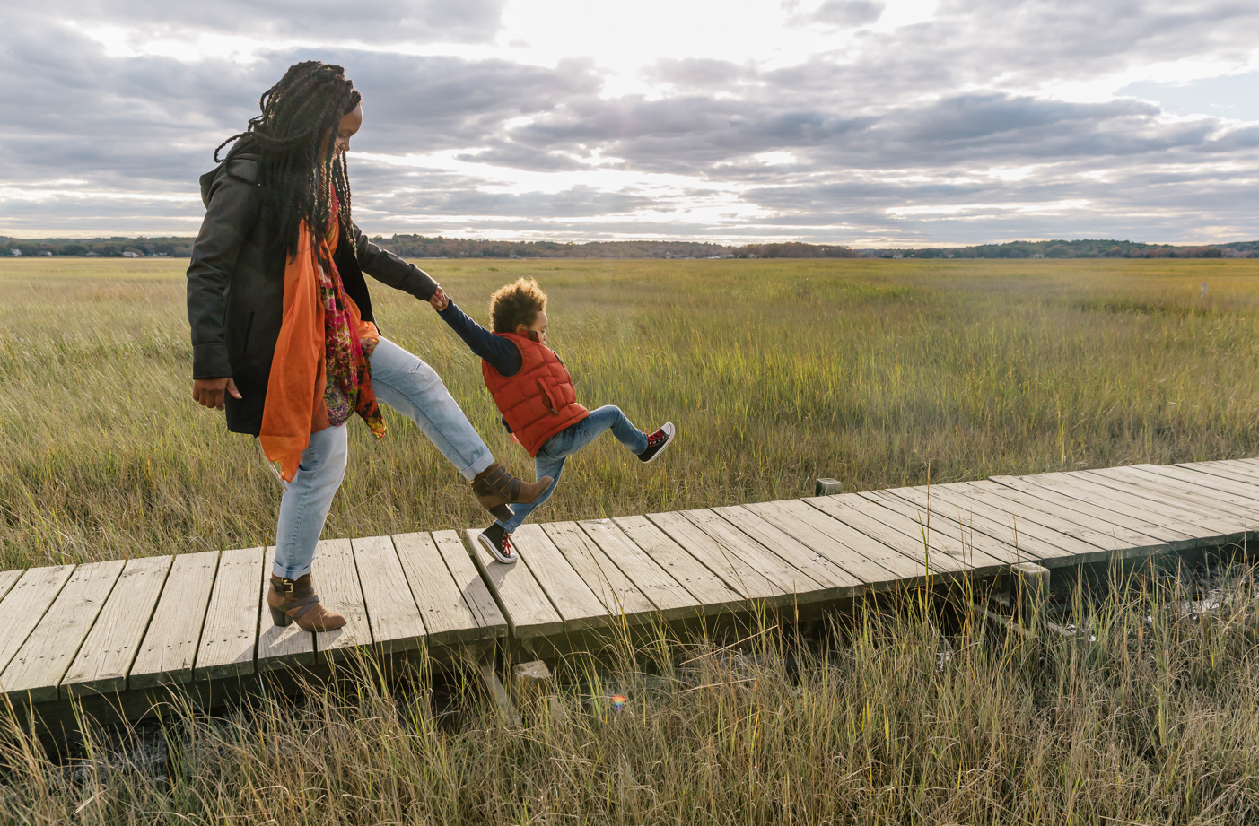 Man and woman strolling down bridge in grassy field