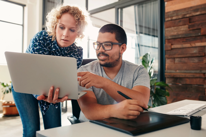 Man and woman reviewing work on laptop