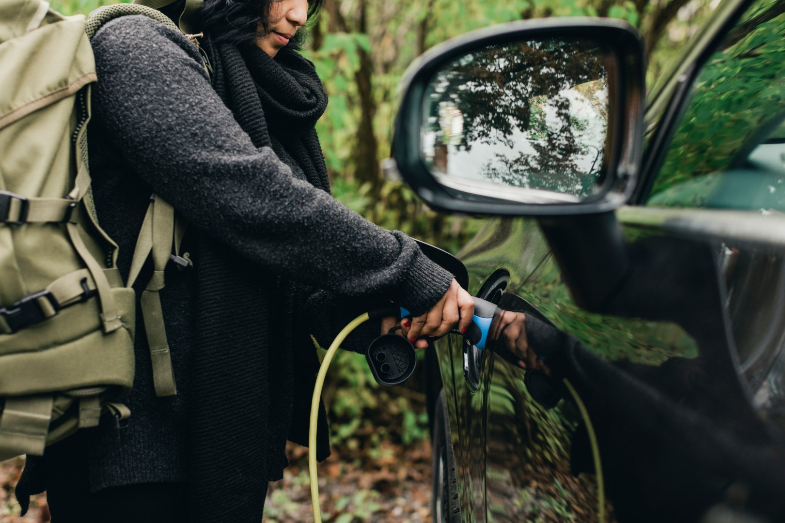 Midsection of mid adult woman charging electric car