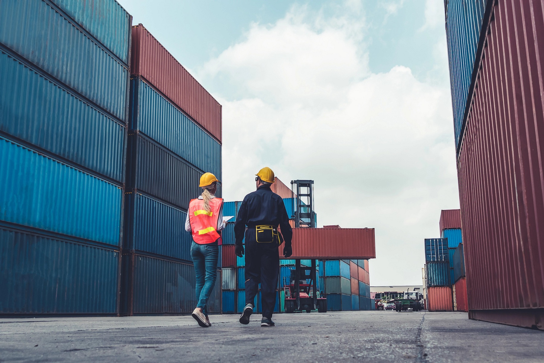 A man and woman walking through area with shipping containers.