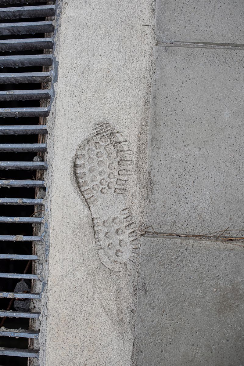 Male footprint imprinted in a sidewalk concrete cement.