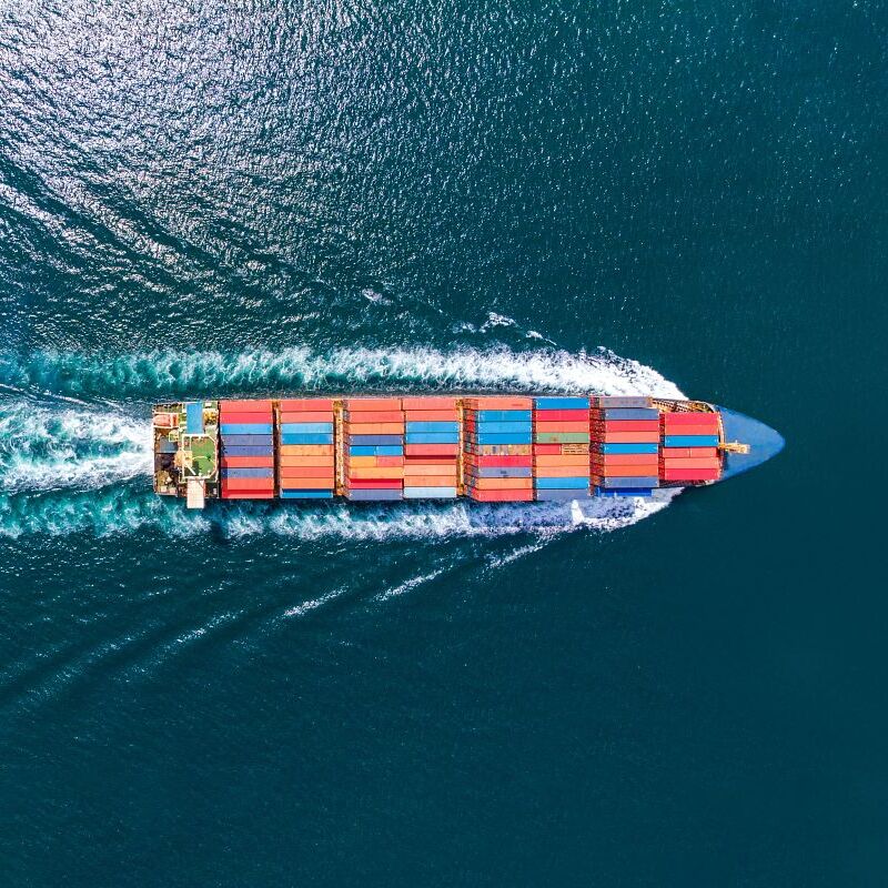 Aerial top view of cargo ship with contrail in the ocean