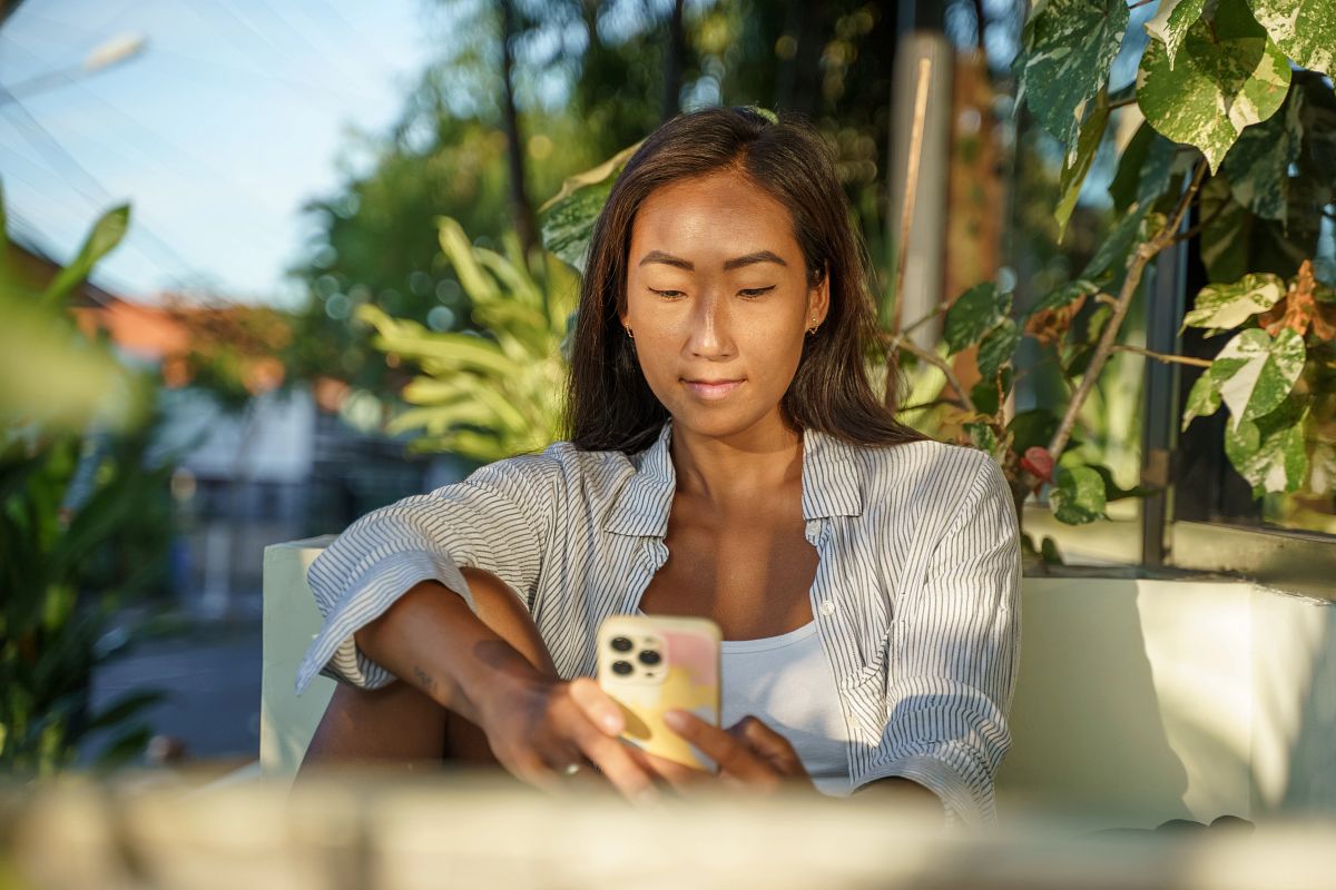 Young woman relaxing with smartphone in cafe booth