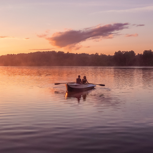 Romantic golden sunset river lake fog loving couple small rowing boat