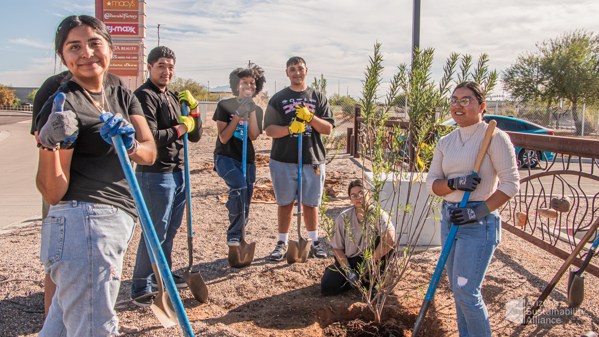 Group of 5 young adults posing for a photo after planting trees, plants and shrubs at the Superstition Springs Transit Center in Mesa, Arizona.