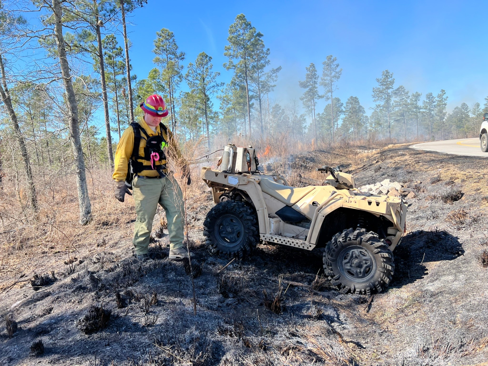 Man walking near quad monitoring a controlled forest burn for a data center build.